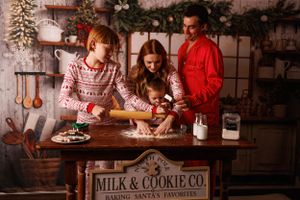 People in cozy jammies bake Christmas cookies together in a festive kitchen decorated for the holiday season.
