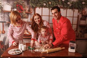 Family gathers around wooden table during holiday season preparing festive treats and decorations together.