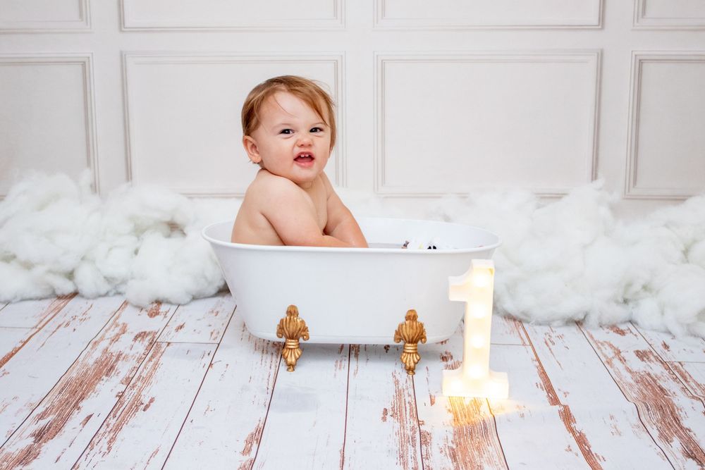 White rustic wooden floor setting with number one candle glowing for first birthday photoshoot.