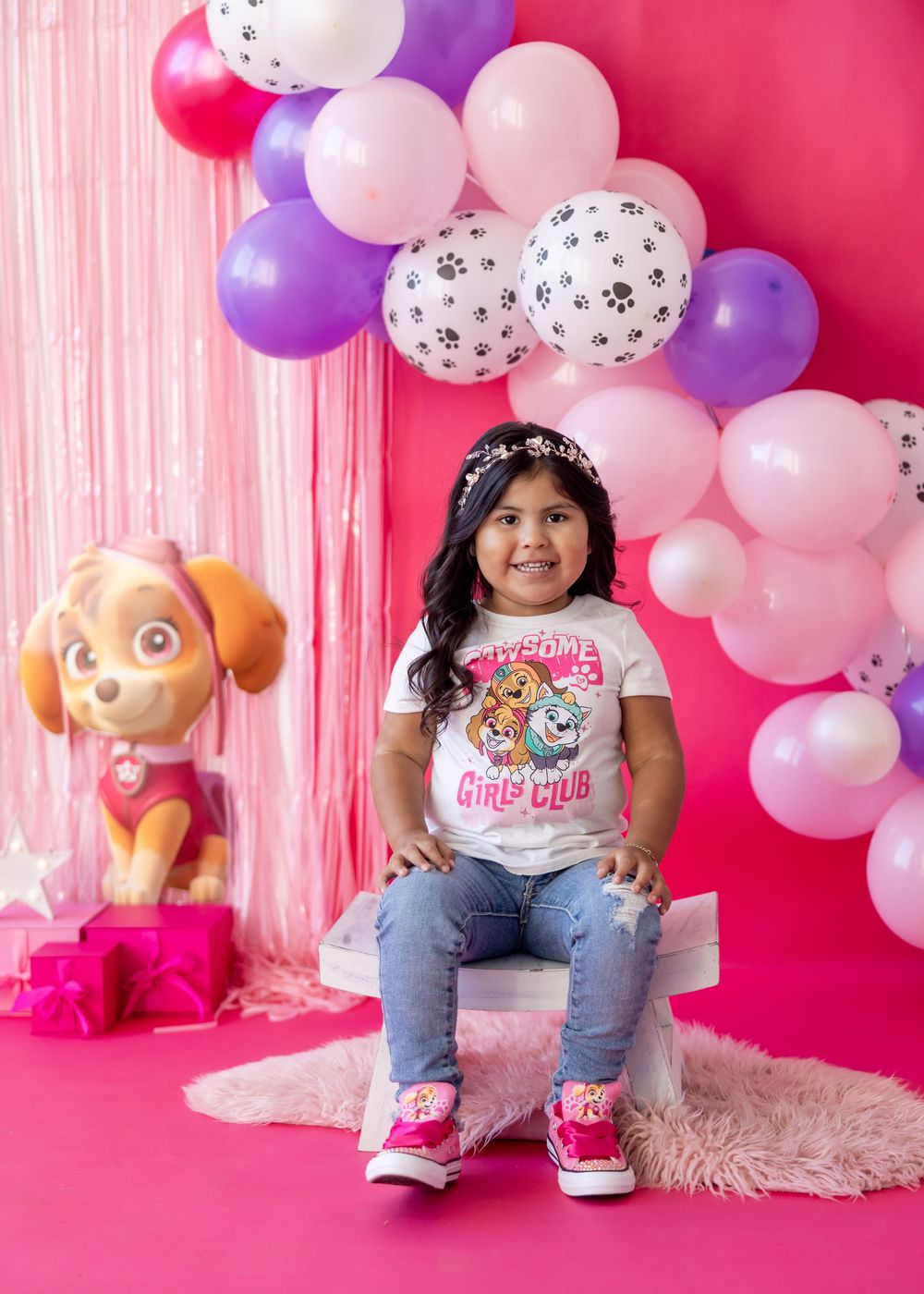 Paw Patrol themed birthday party setup with pink and purple balloon arch and plush Skye character decoration.