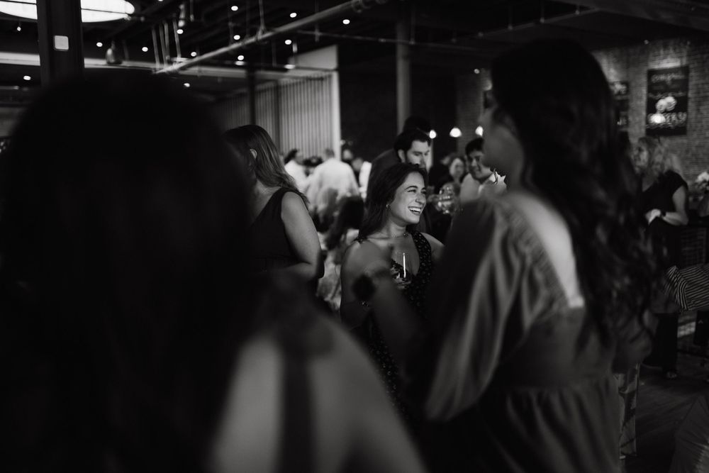 Candid black and white photo of a crowded social gathering in a dimly lit venue.