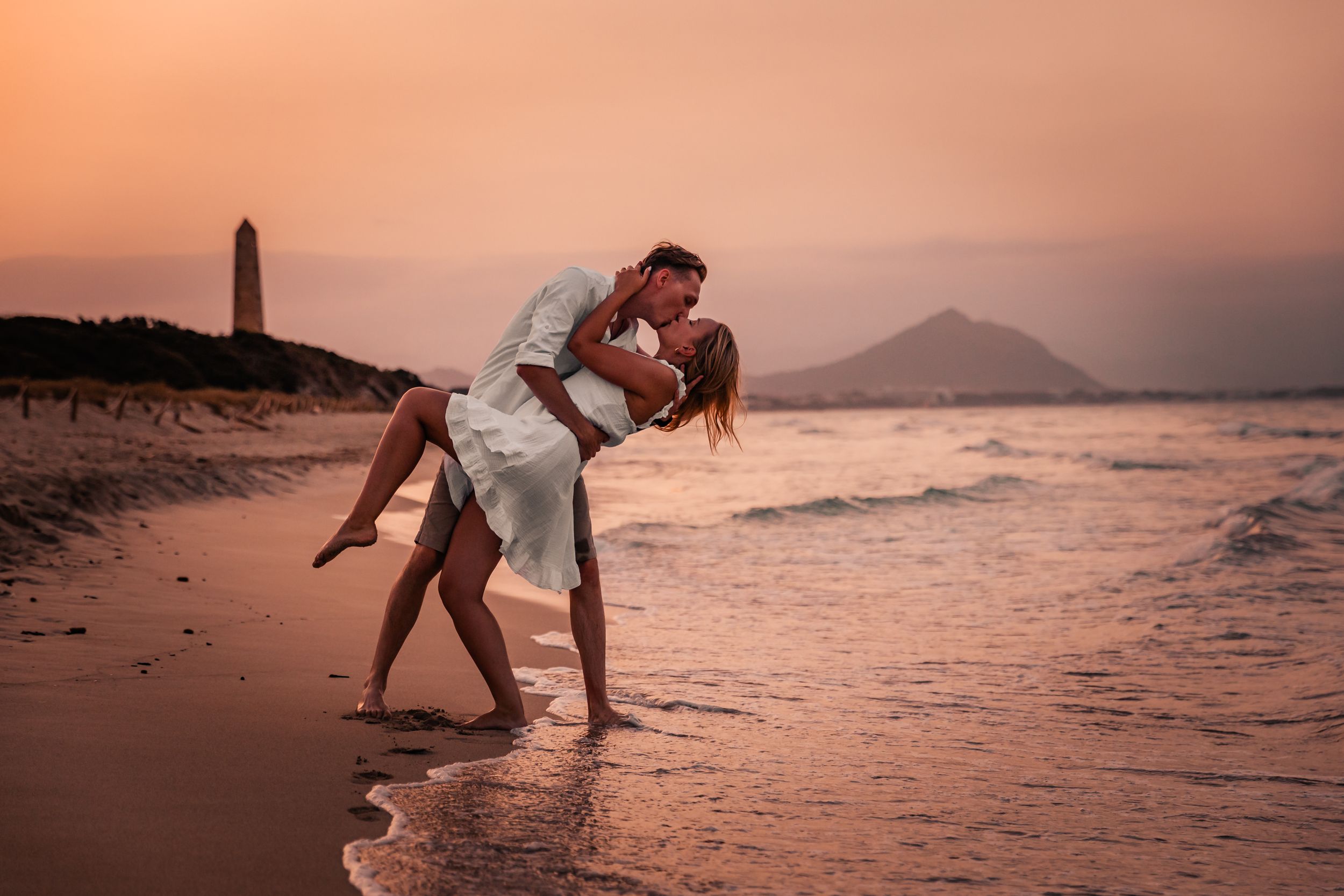 Playful couple moment on a Mallorca beach at sunset during a romantic couple photoshoot.