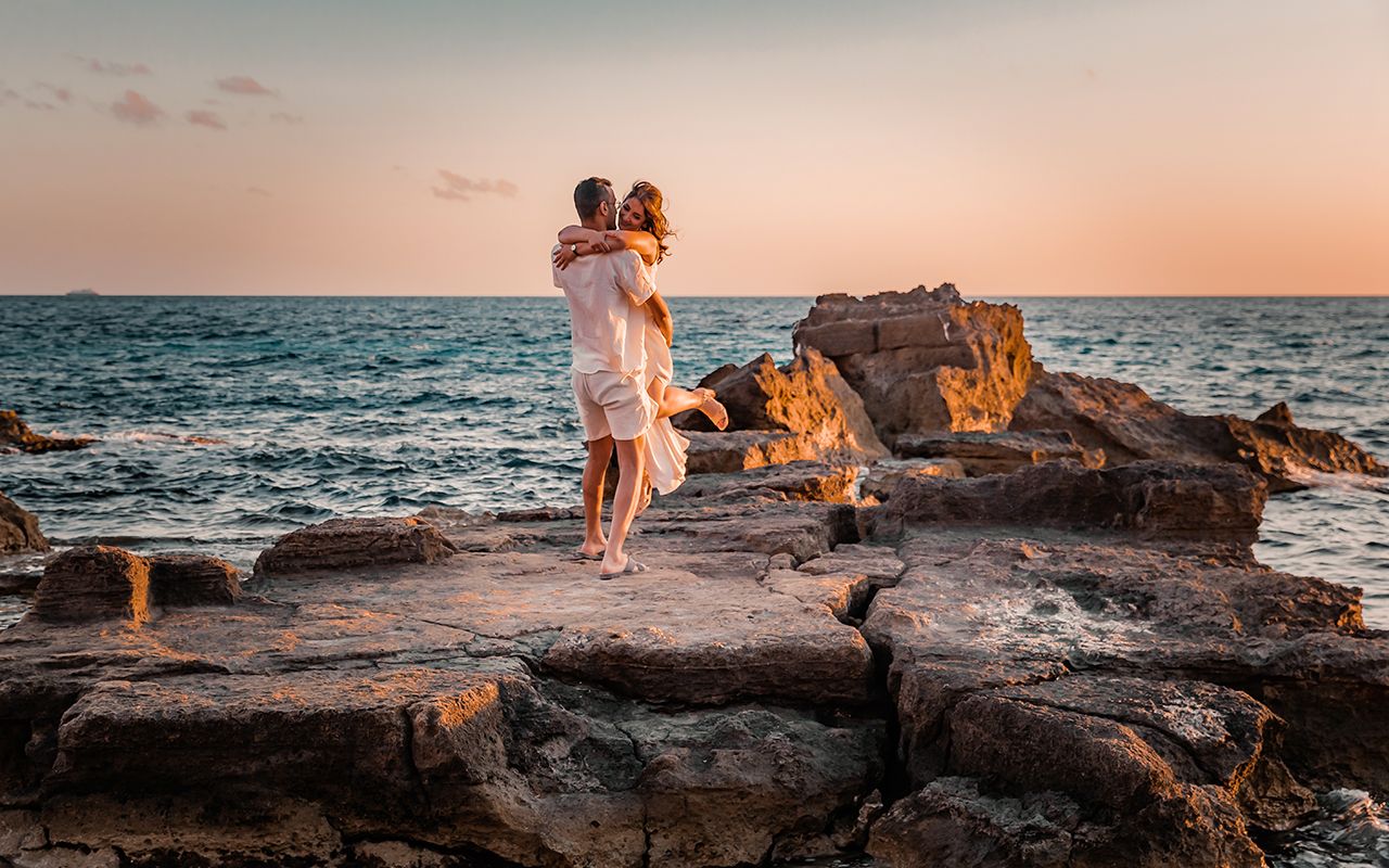 Romantic couple dancing and hugging on seaside rocks during a golden hour Mallorca couple photoshoot.