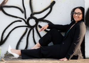 Casual portrait against graffiti wall showing relaxed pose in black outfit.
