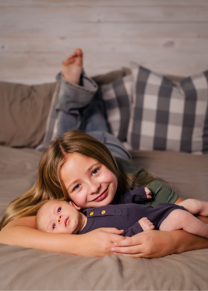 Two people laying together on gray checkered bedding sharing a tender moment.