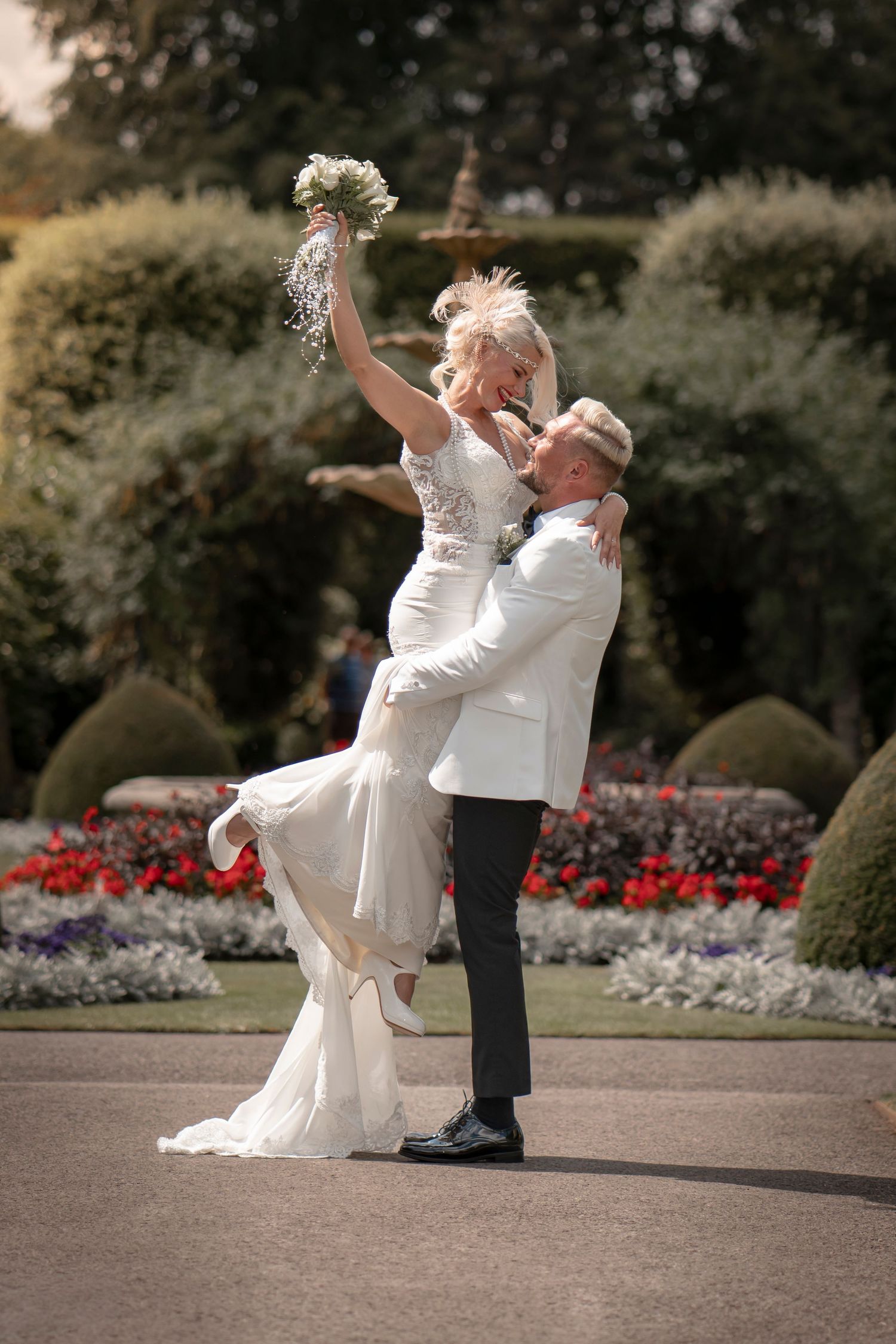 Couple performs romantic dip pose in garden setting with flower beds. Brodsworth gardens wedding photography. Doncaster wedding photography