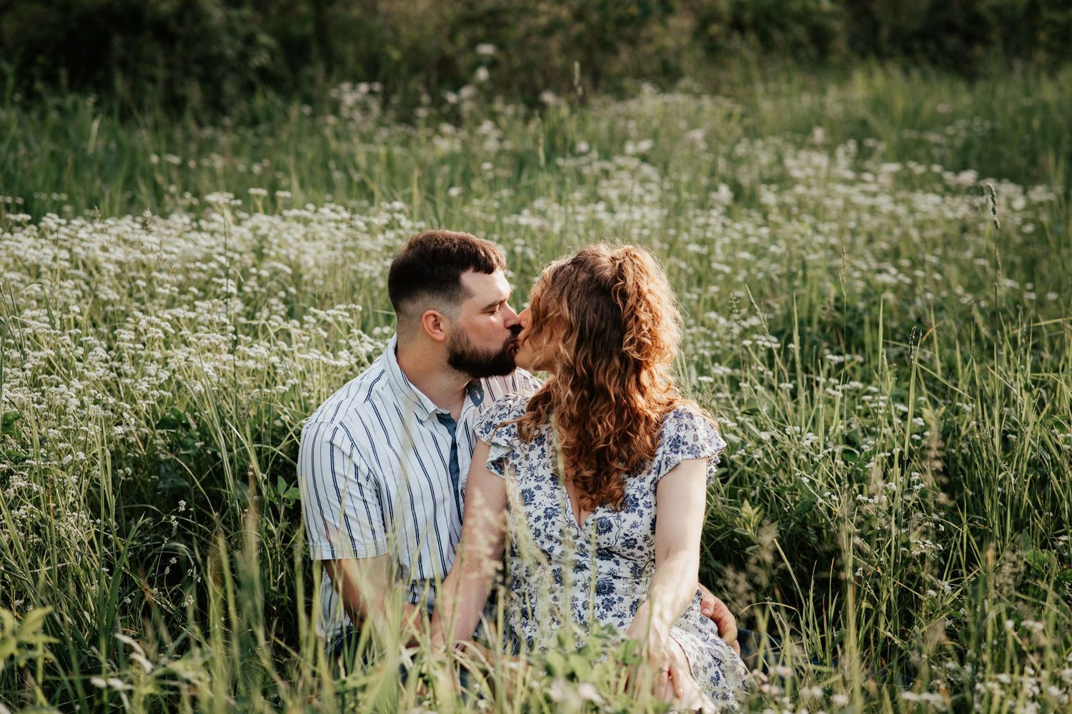 A couple shares an intimate moment in a wildflower meadow during summer.