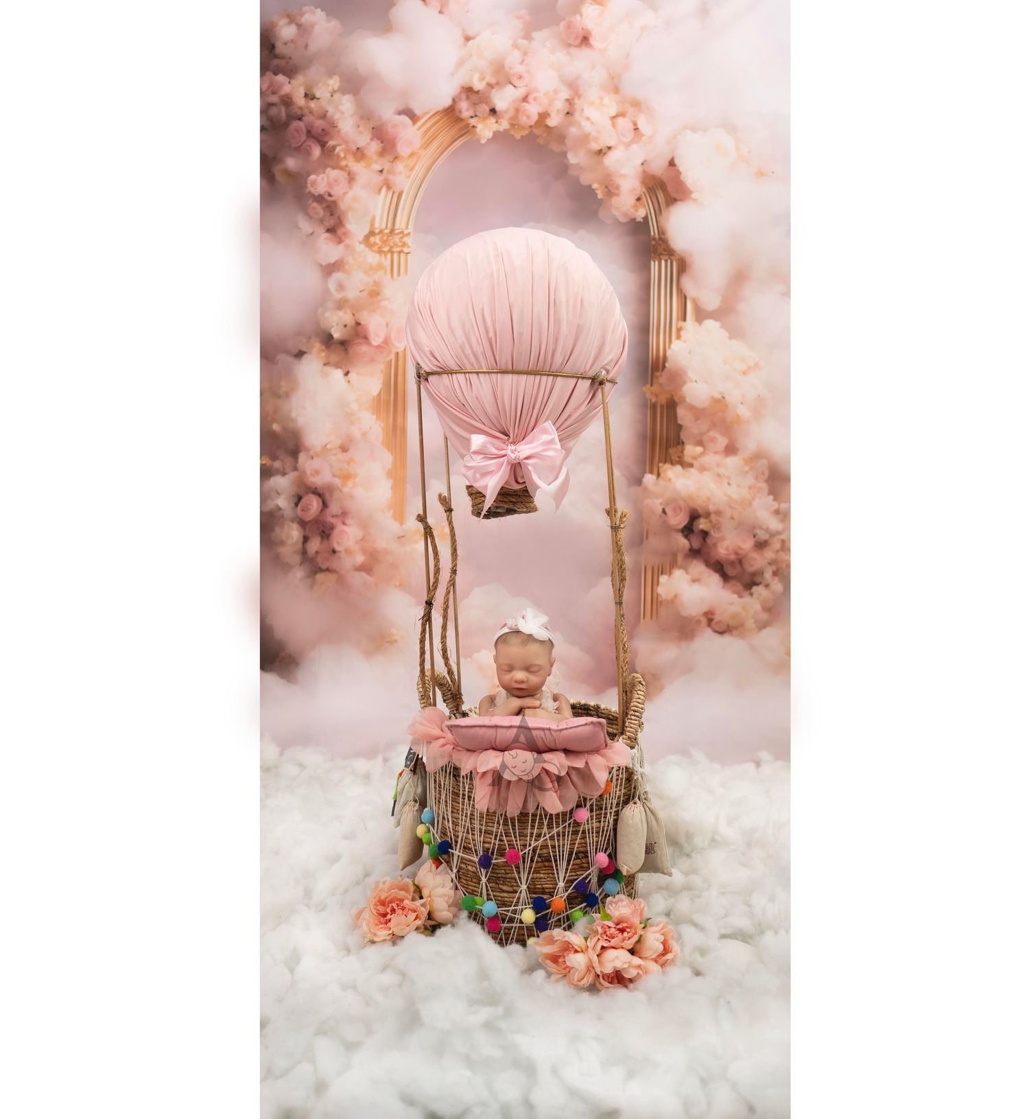 Dreamy pink photography setup with a vintage swing chair adorned with flowers and soft clouds.