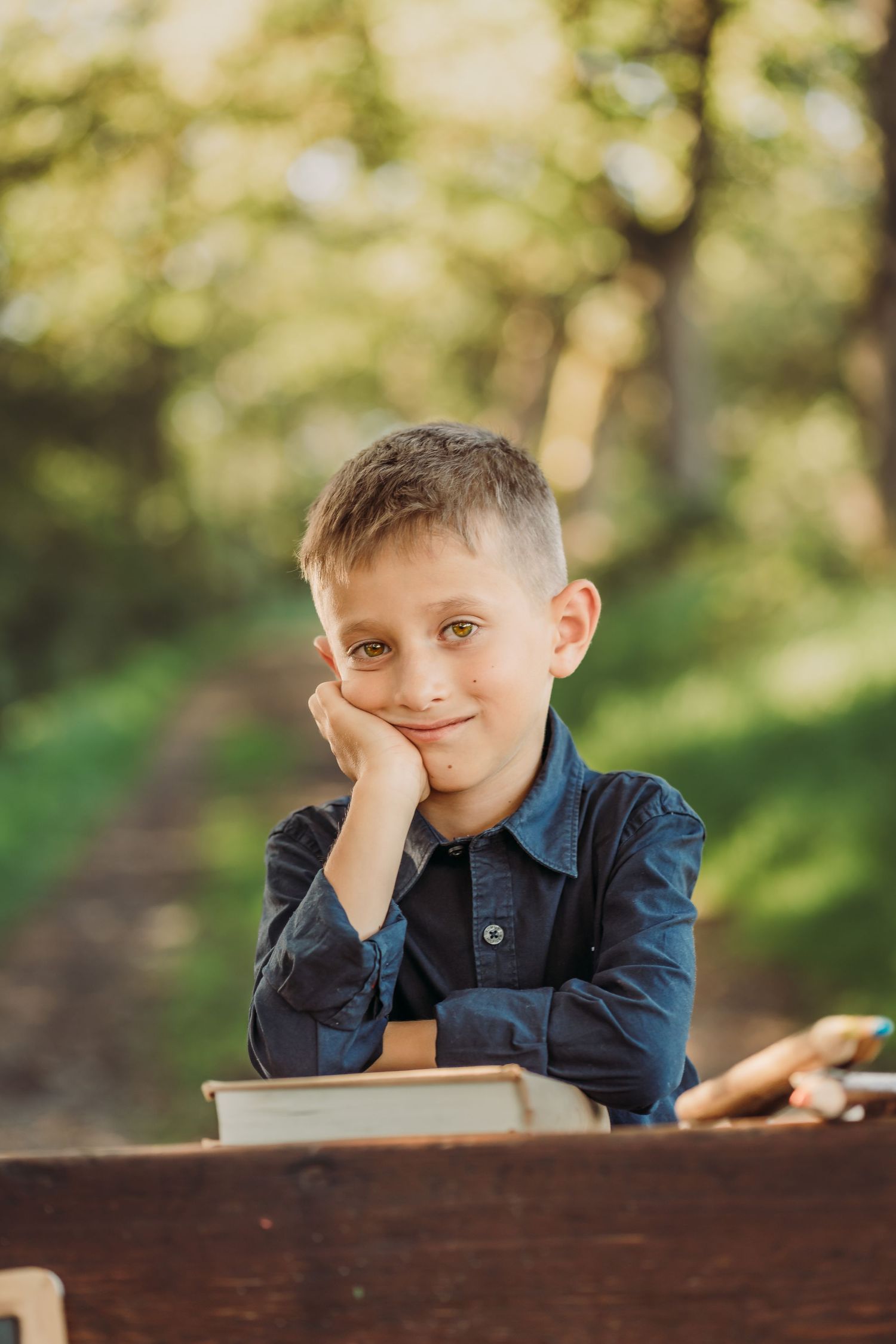 Portrait of student leaning on desk in outdoor forest setting.