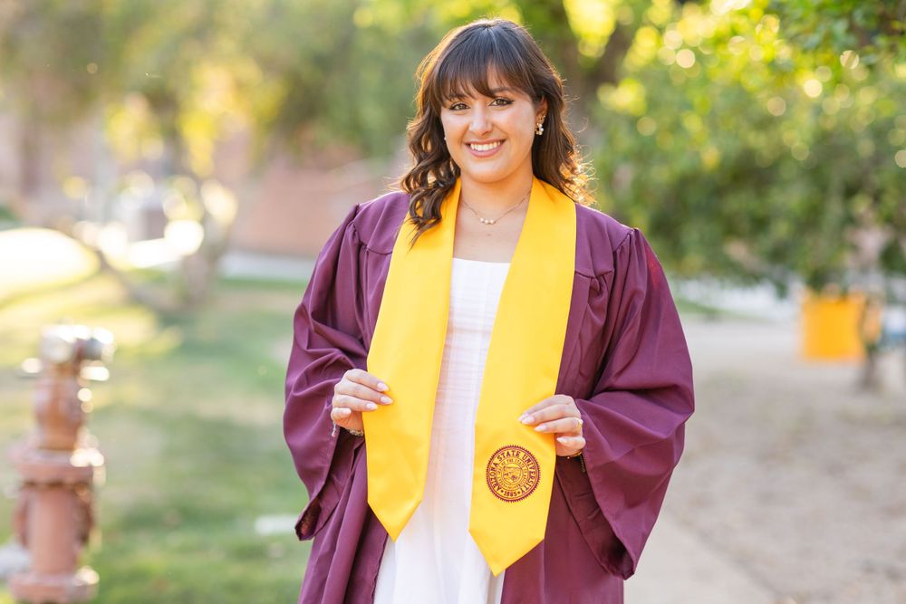 Graduation photo featuring maroon cap and gown with gold honors stole.