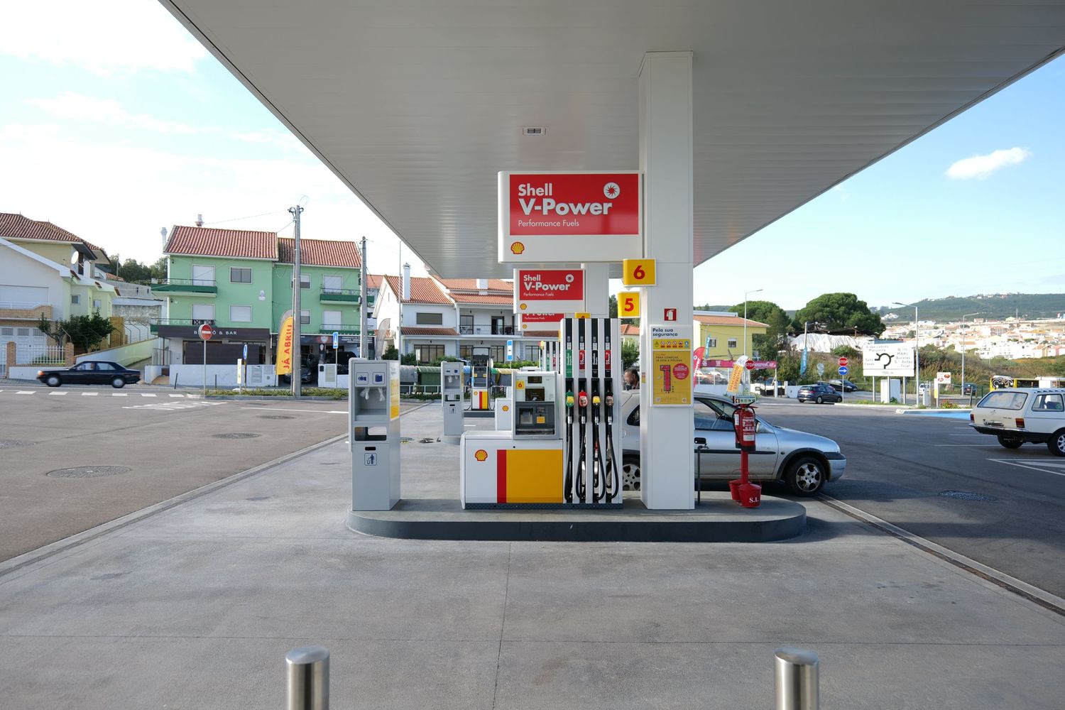Shell V-Power gas station with fuel pumps under a canopy in a suburban area.