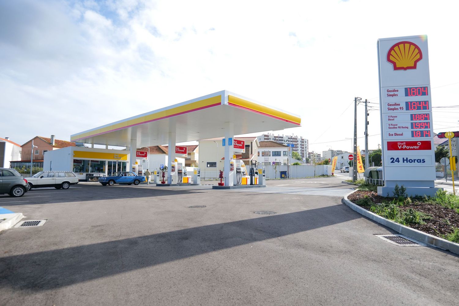 Shell gas station with fuel pumps and price sign in a suburban neighborhood.