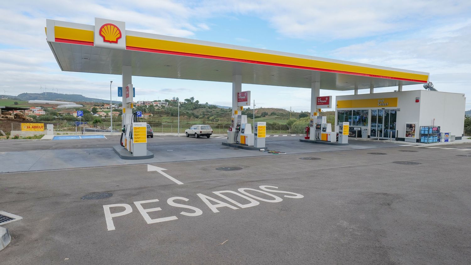 Shell gas station with PESADOS marked pavement and fuel pumps under a canopy.