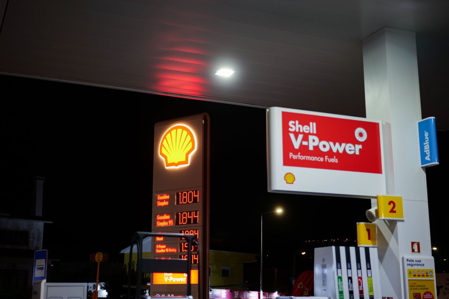 Shell V-Power Performance Fuel station sign illuminated at night with fuel prices displayed.
