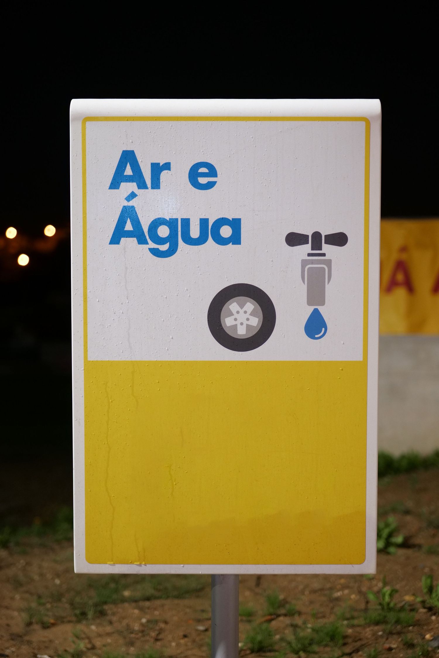 Yellow and white Shell gas station sign reading Ar e Agua with tire and water tap icons.