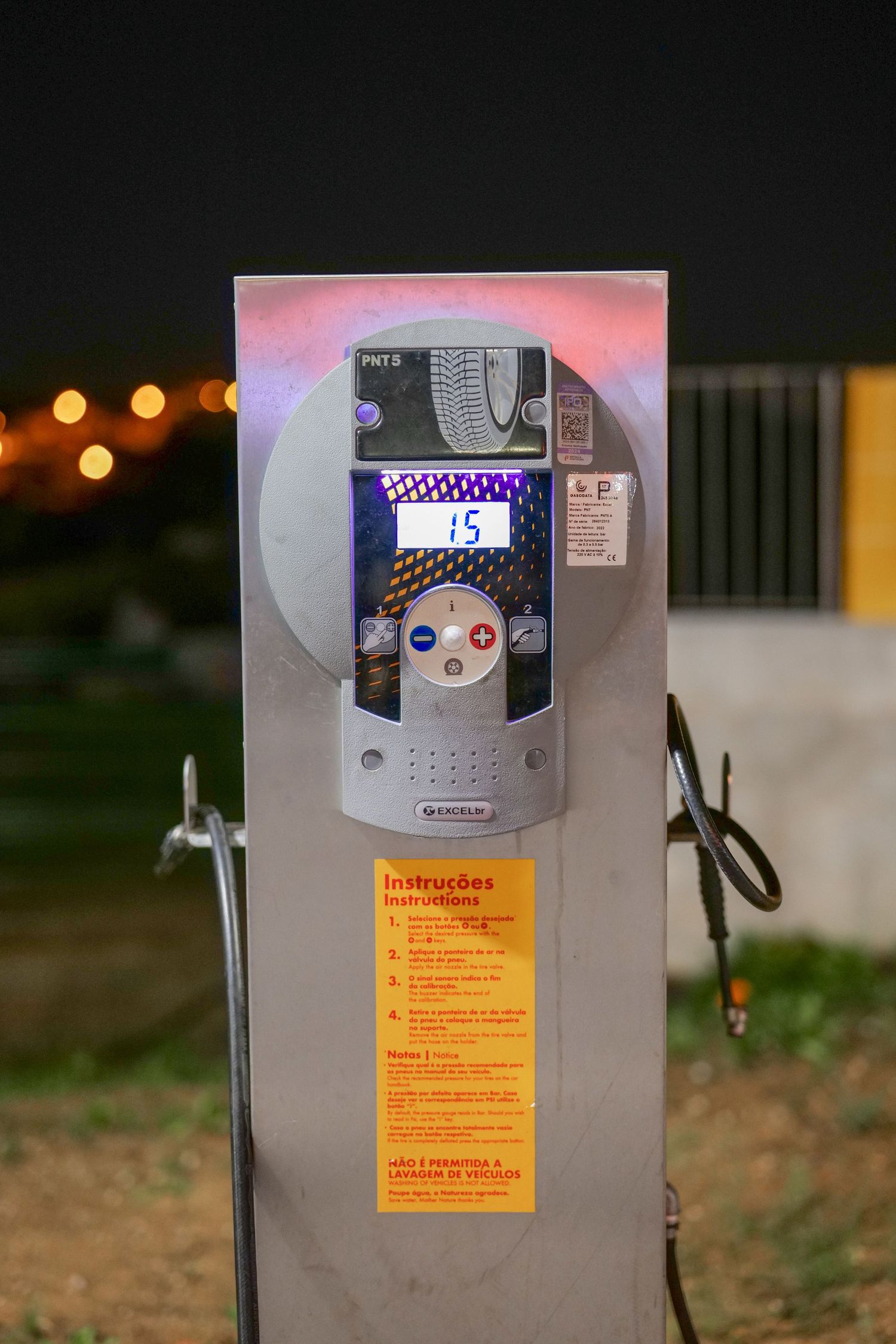 Shell gas station air pressure machine displaying 15 PSI with instructions panel at night.