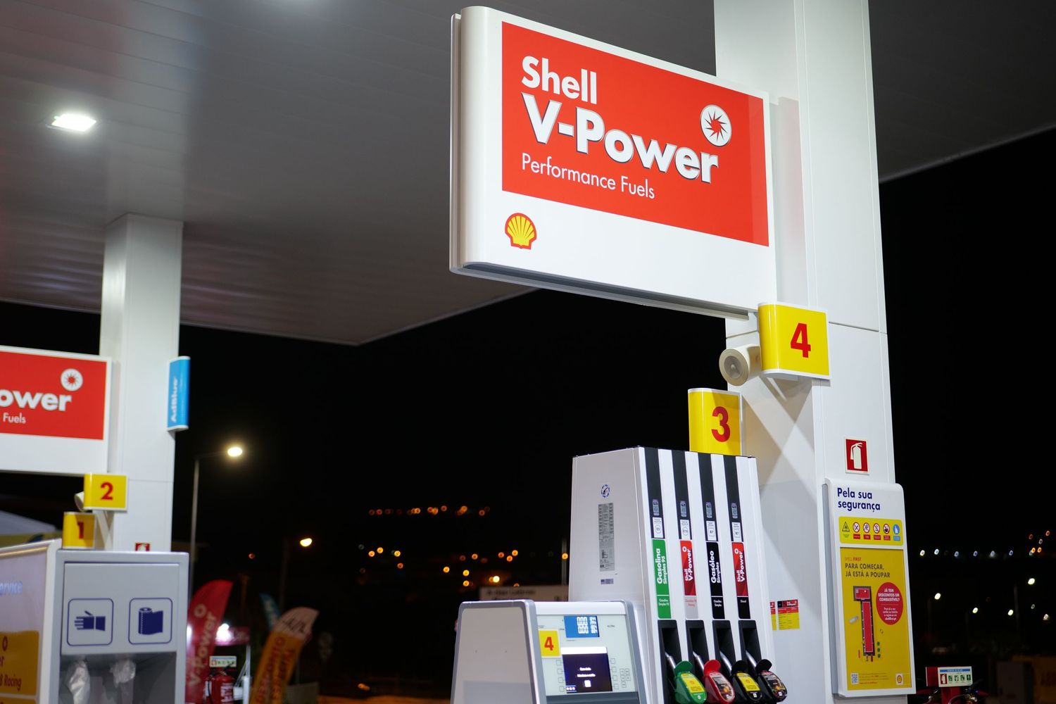 Shell V-Power Performance Fuel pump station with multiple fuel dispensers illuminated at night.