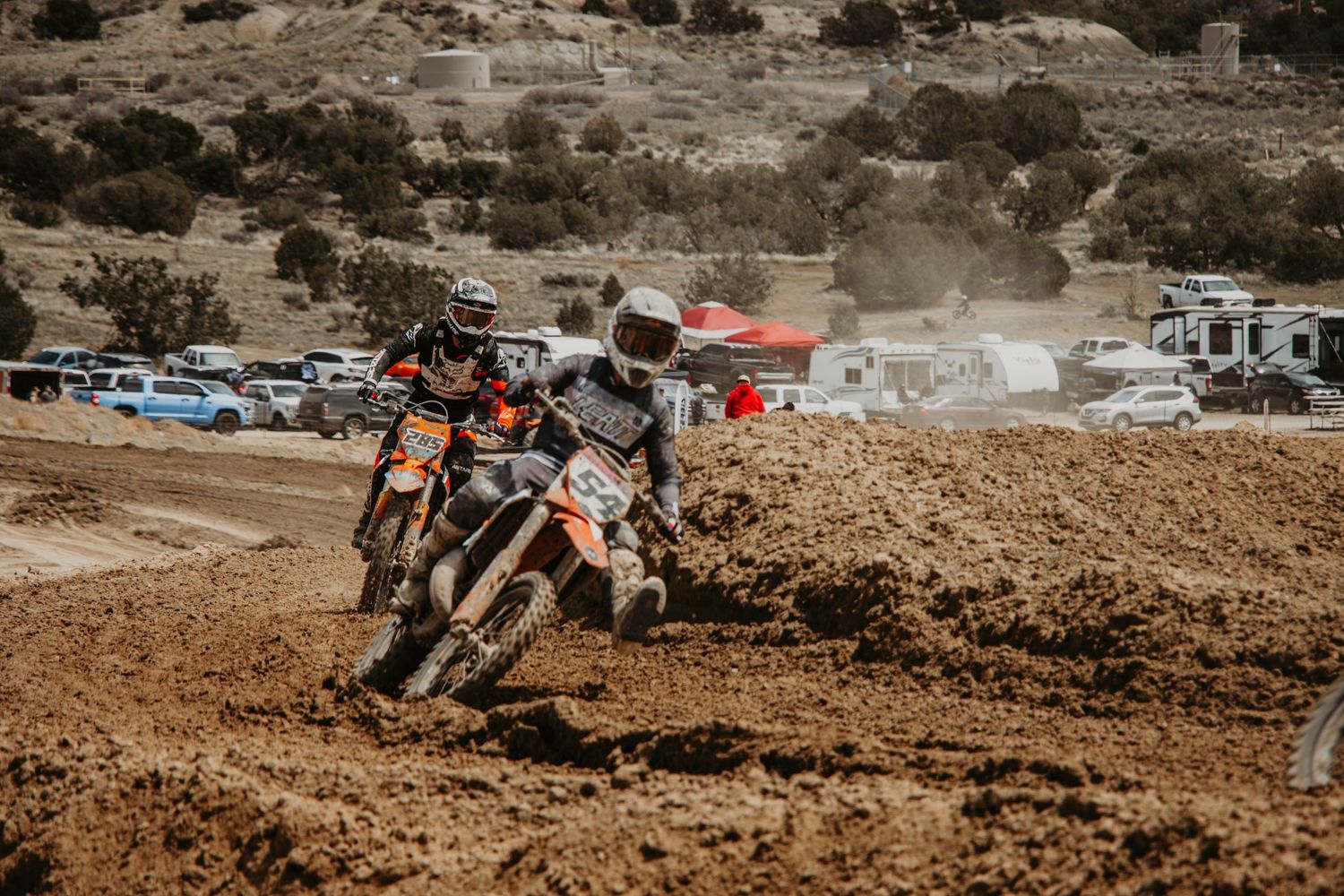 A motocross rider leans into a turn on a dirt track, kicking up dust during an intense race.