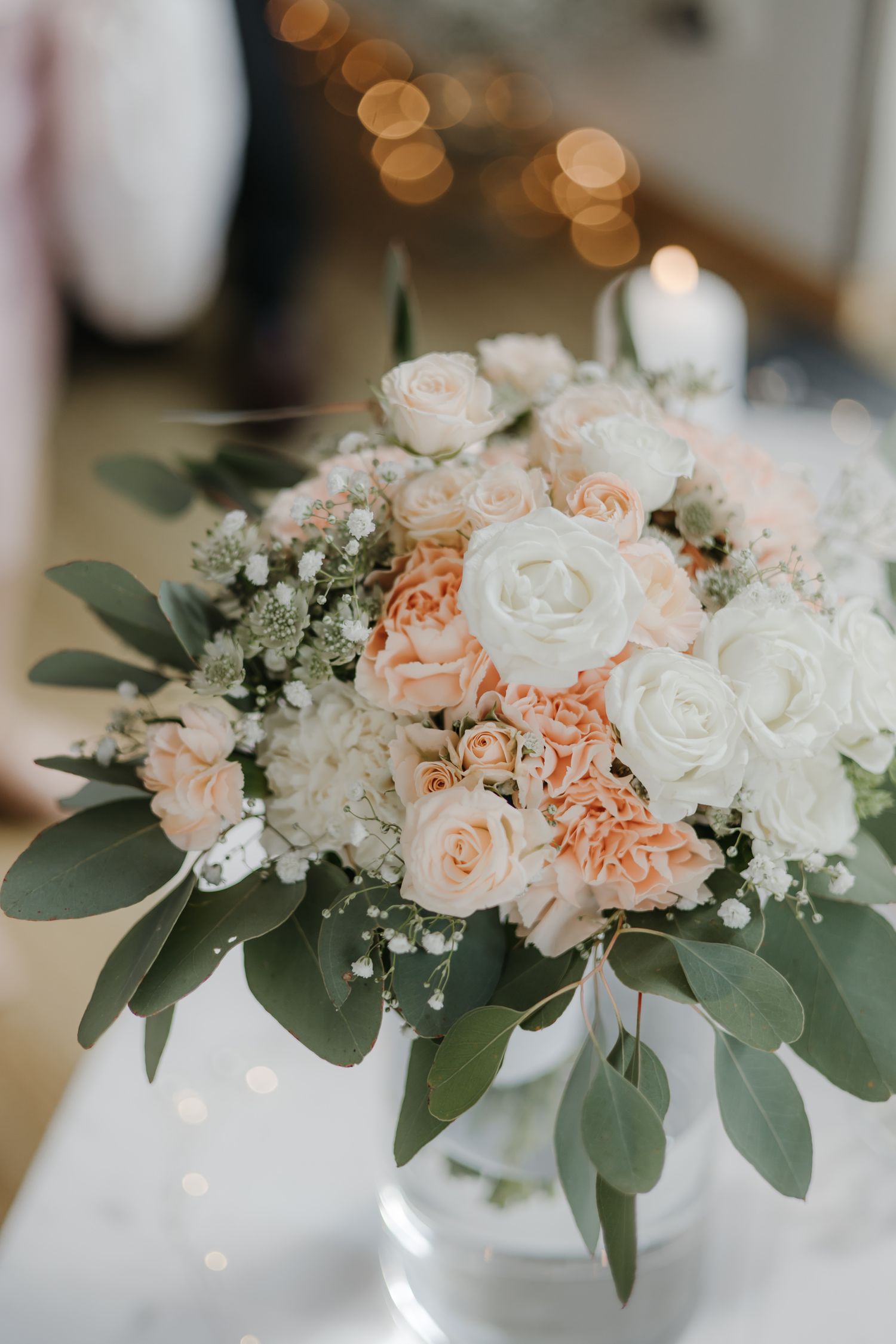 Woman in white turtleneck sweater holding delicate baby's breath flowers while looking down.