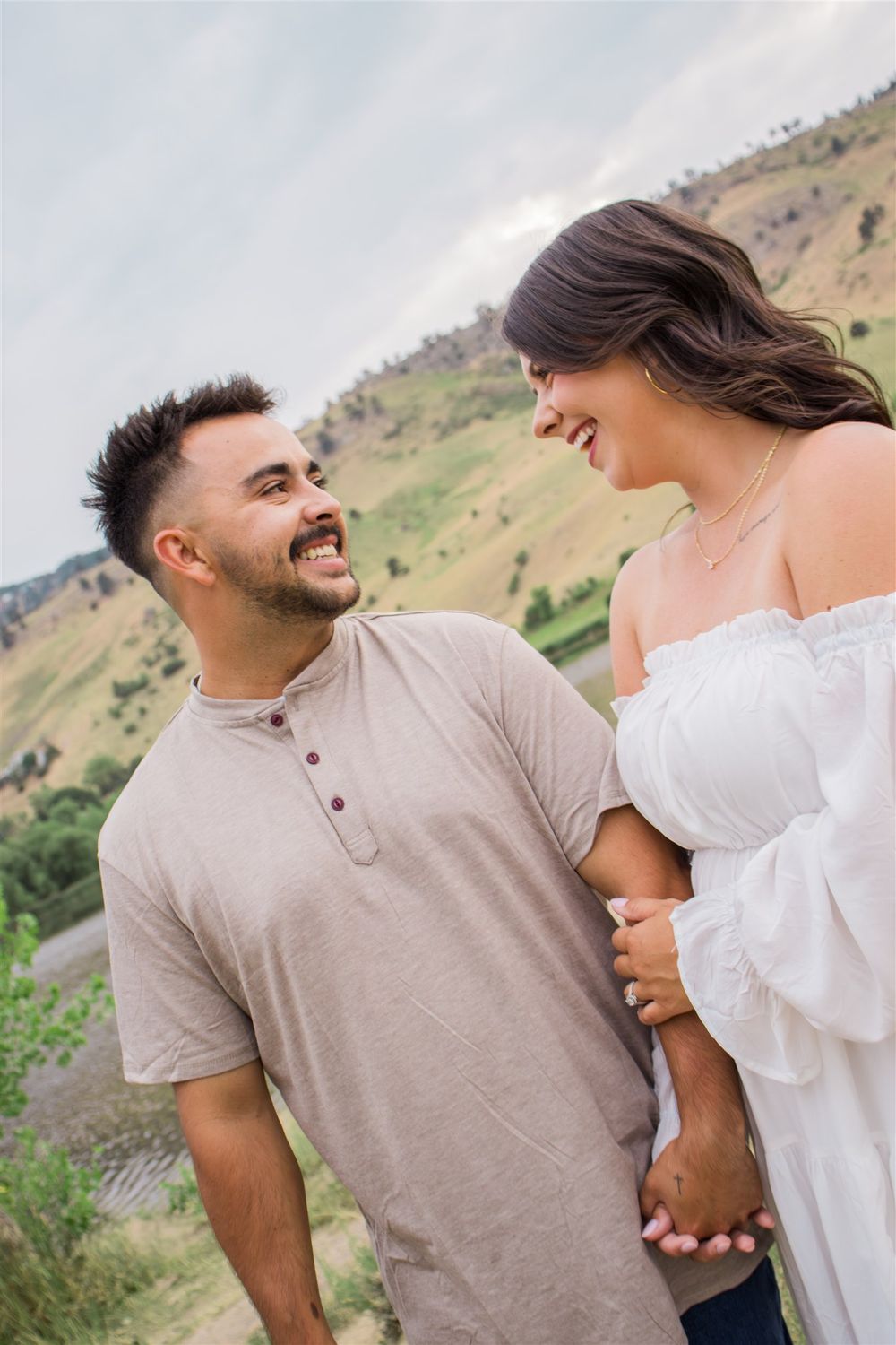 A loving couple in casual attire share affectionate moments against a scenic mountain backdrop.