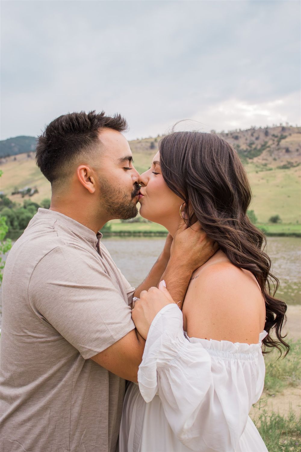 Romantic couple sharing intimate moments in front of a scenic mountain landscape.