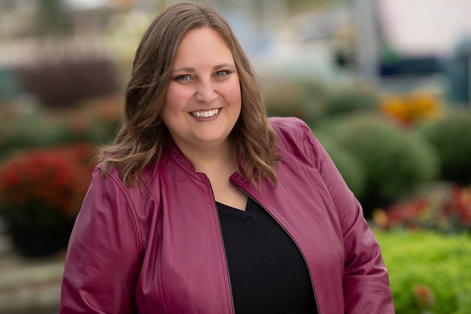 Life coach posing for a headshot for her business. Wearing Fuchsia moto jacket