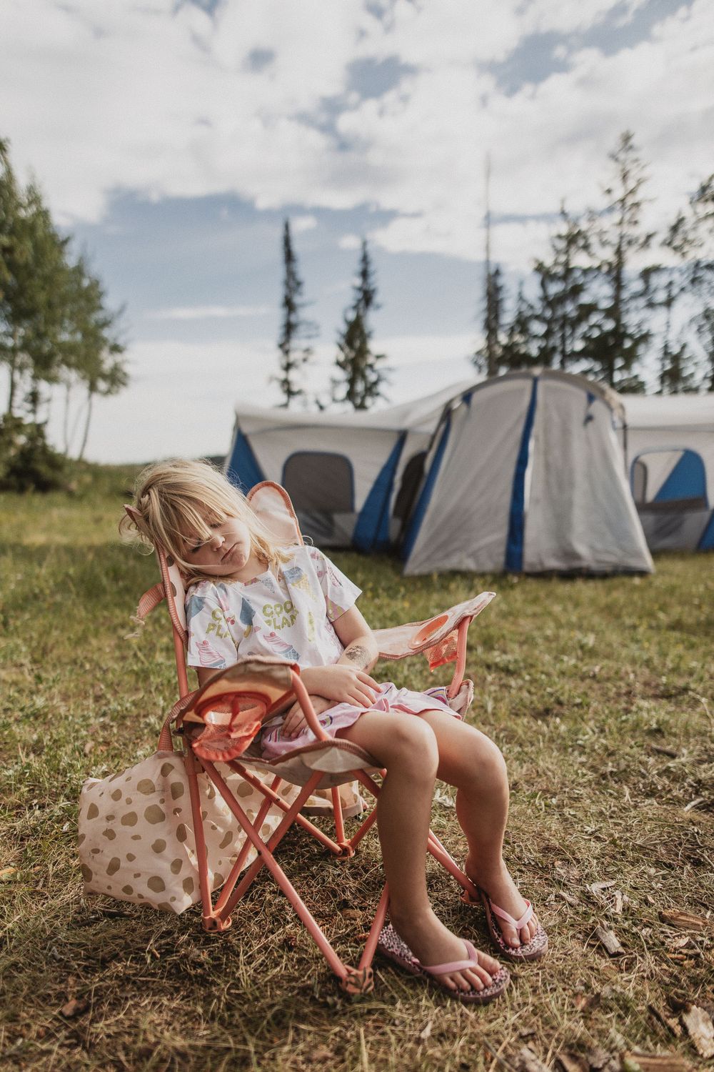 Camping scene with folding chair and tent setup in grassy field.