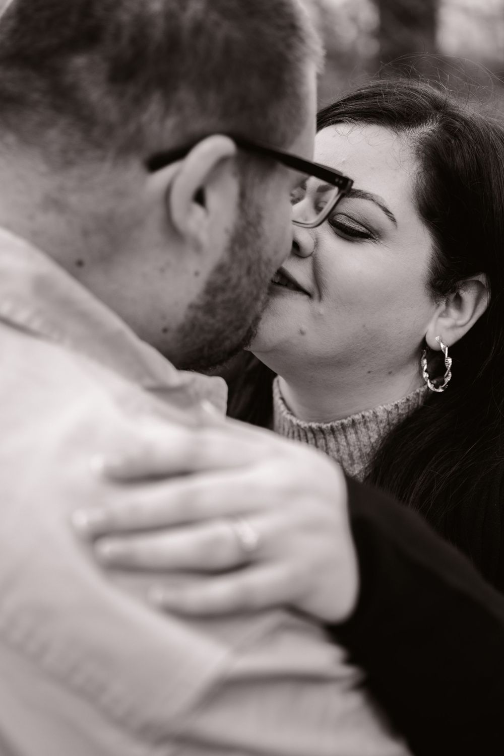 Romantic black and white close-up portrait of an intimate couple about to kiss wearing casual winter attire.