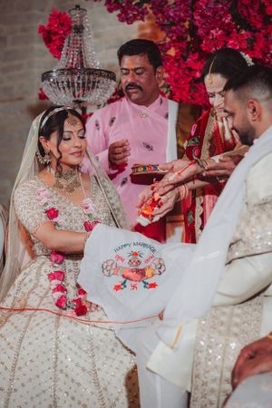 Traditional South Asian wedding ceremony with participants in formal attire under crystal chandelier.