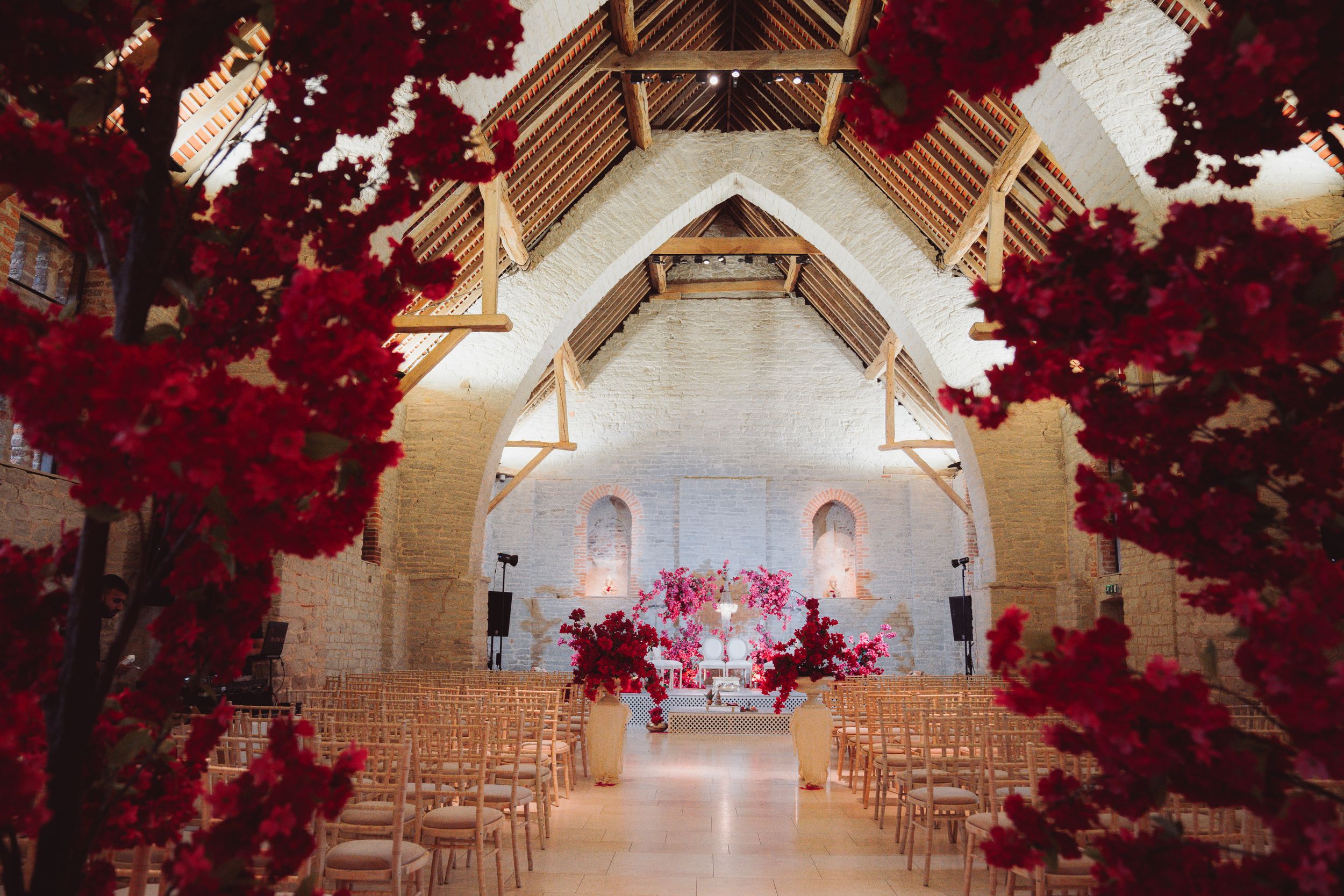 Wedding ceremony venue with dramatic red floral arrangements framing a white arched altar.