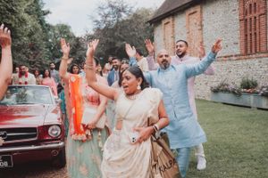 Joyful guests in colorful attire dancing during an outdoor celebration.