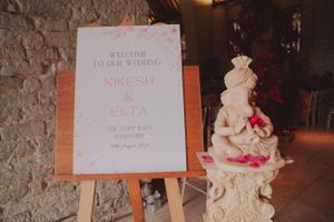 A welcome sign and elegant white wedding cake on display at a wedding reception venue.