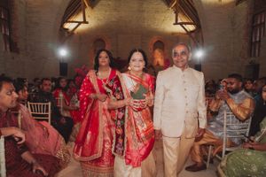 Traditional Indian wedding ceremony with attendees in colorful attire inside a stone-walled venue.