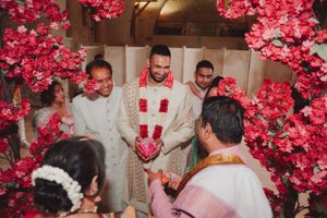 Wedding ceremony with bright pink floral arrangements and traditional Indian attire.