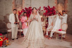 Wedding celebration in elegant venue with red floral arrangements and white brick walls.