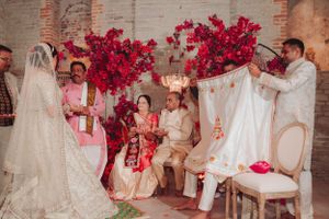 Wedding ceremony gathering with dramatic red floral arrangements and vintage chairs.