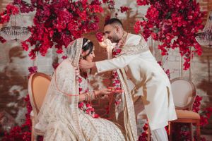 Wedding ceremony moment captured under a canopy of bright red flowers with elegant decor.