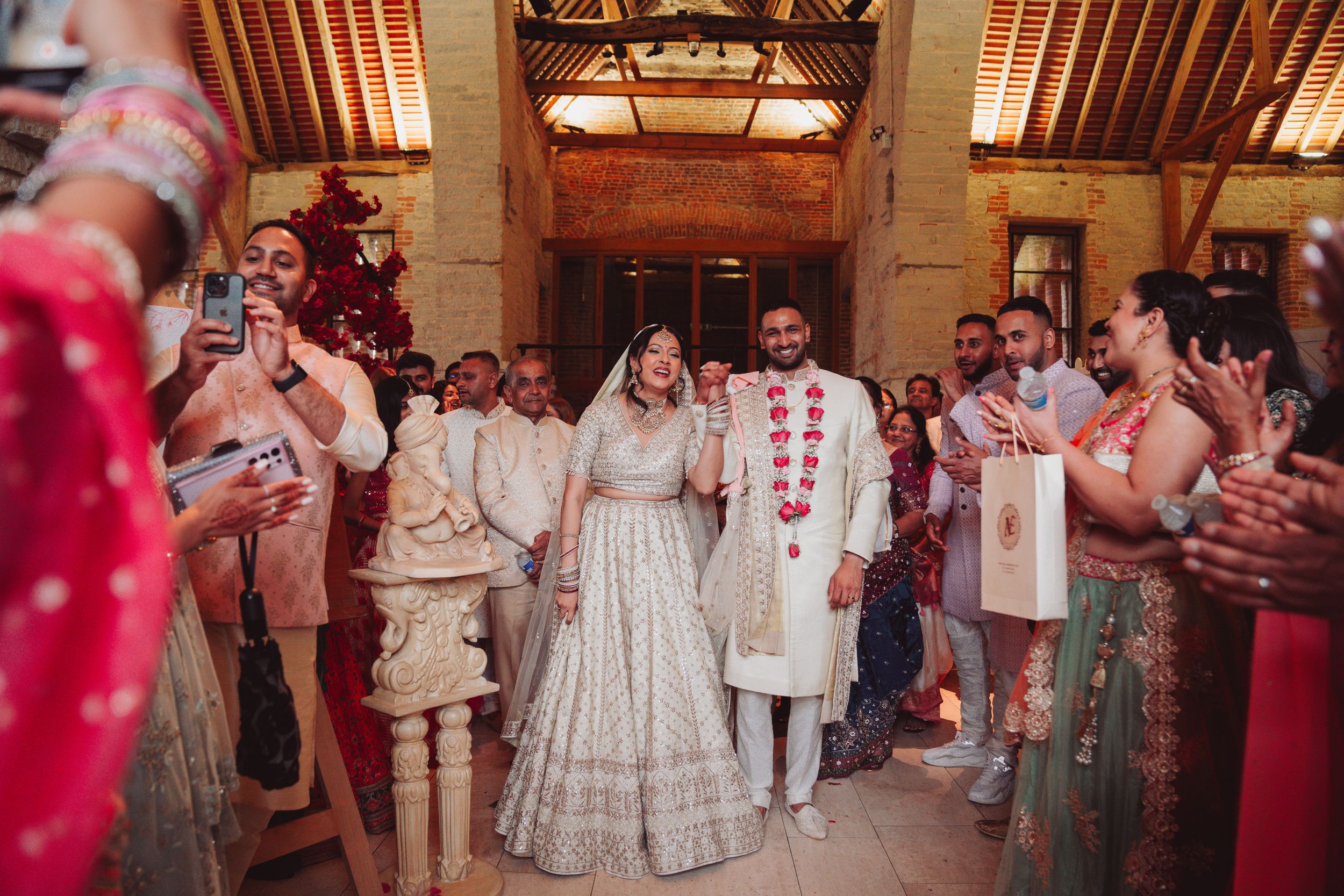 Wedding celebration in stone venue with guests lining pathway in traditional attire.