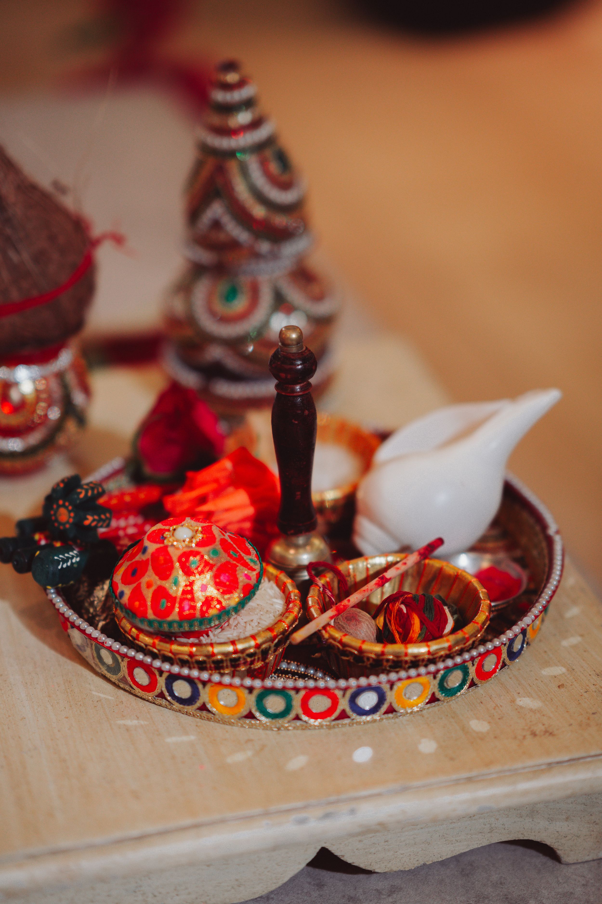 Decorative wedding ritual items displayed on an ornate tray with colorful traditional elements.