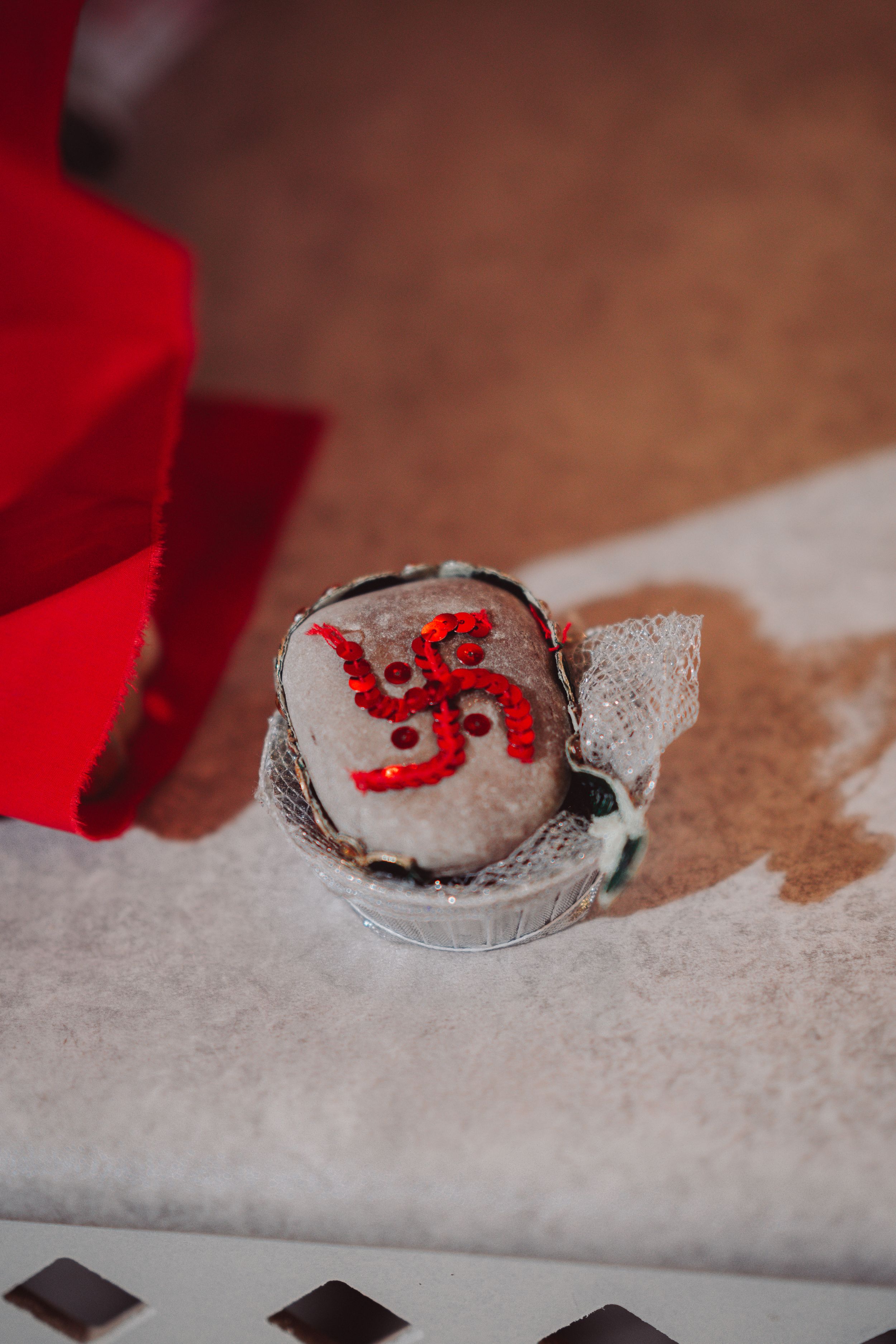 Close-up of a decorative stone with red Sanskrit symbol against white textured background.