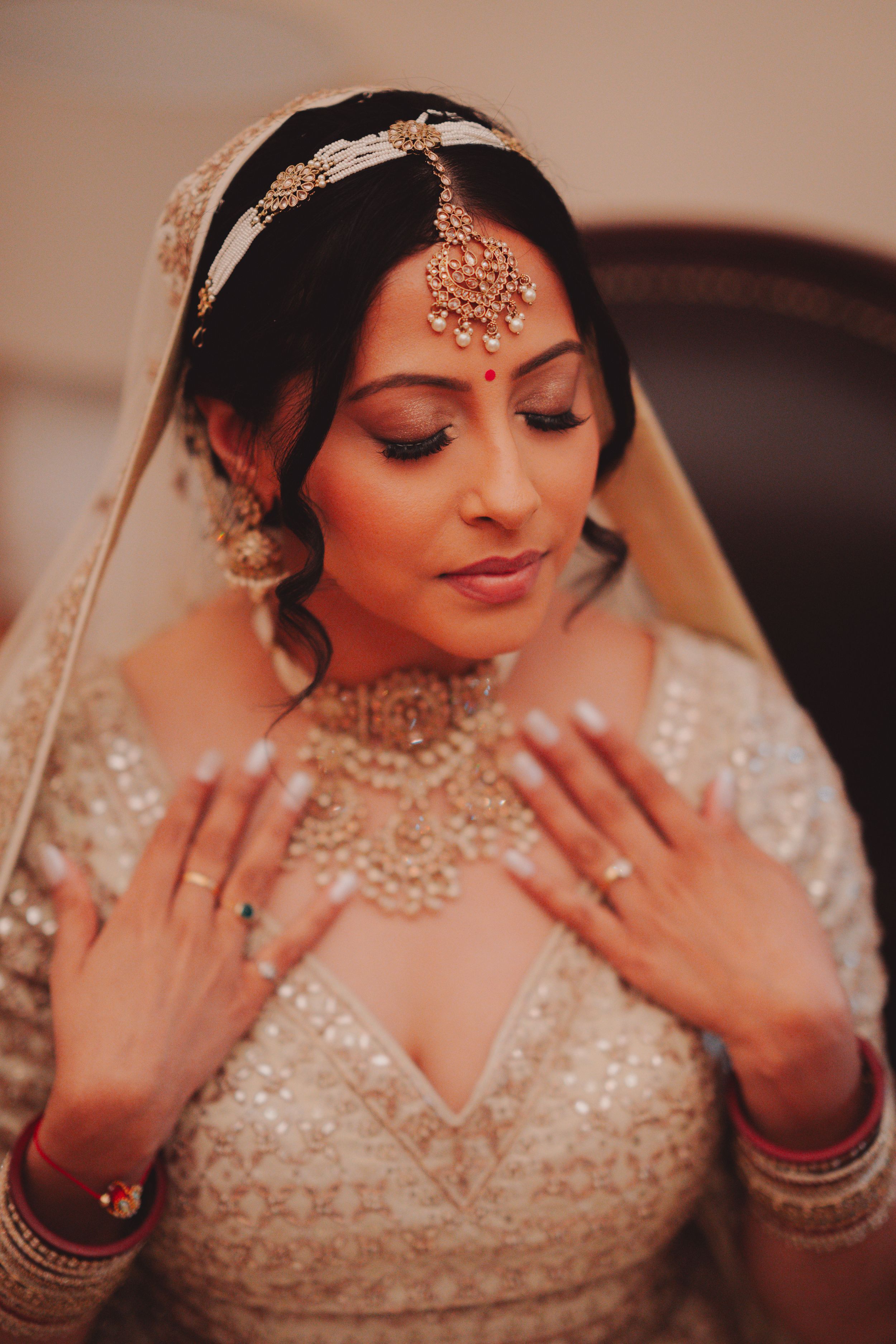 Traditional Indian bridal jewelry and makeup with ornate headpiece and delicate embroidered details.