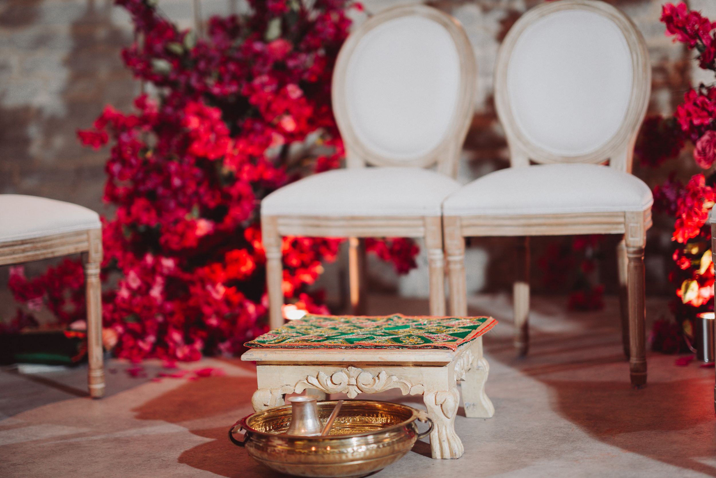 Elegant white chairs arranged near red floral decorations with ceremonial items on display.