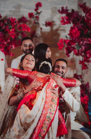 Joyful moment during Indian wedding celebration with vibrant red decorations.
