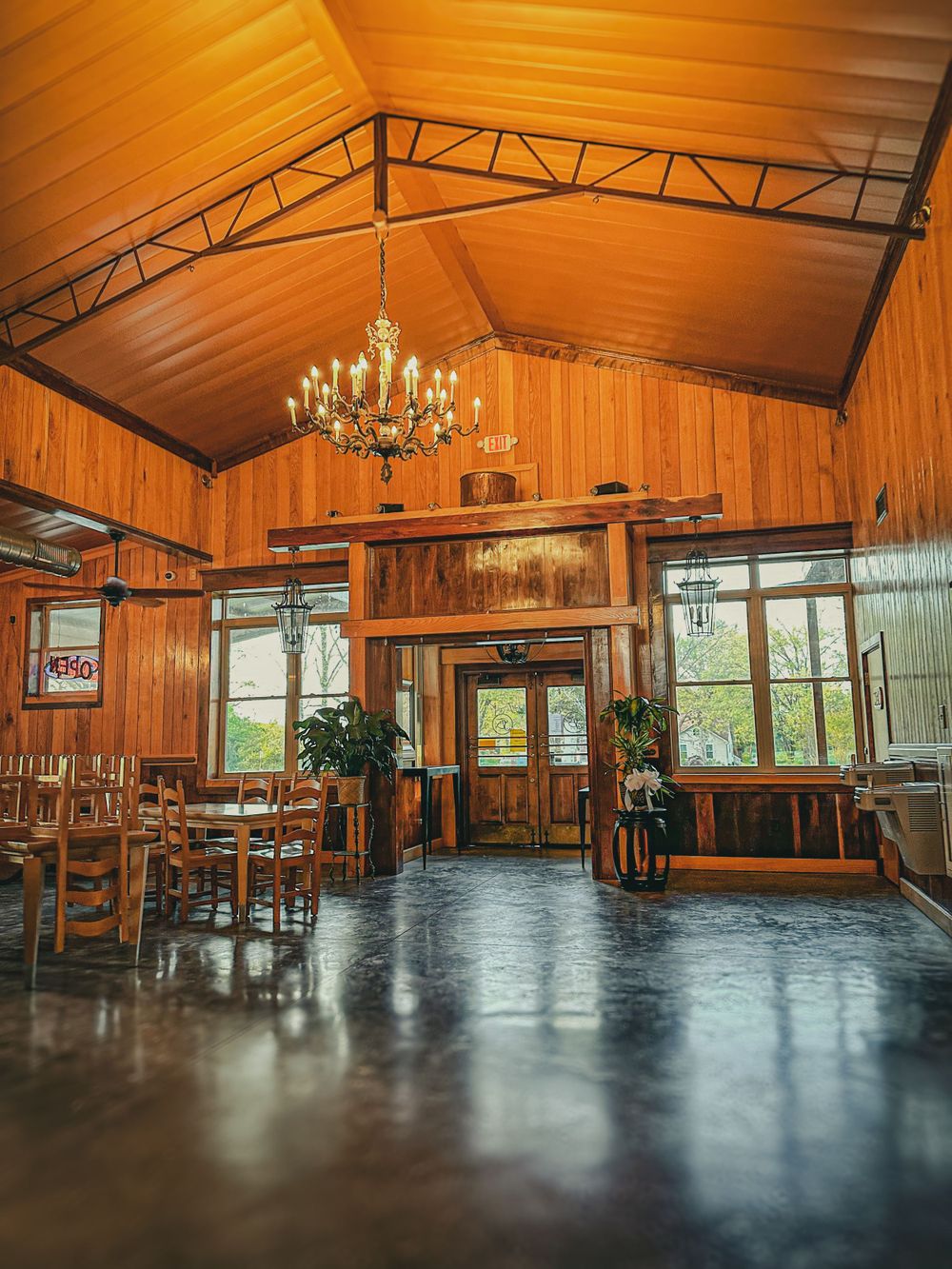 Rustic wooden lodge interior with vaulted ceiling, chandelier, and warm amber lighting throughout.