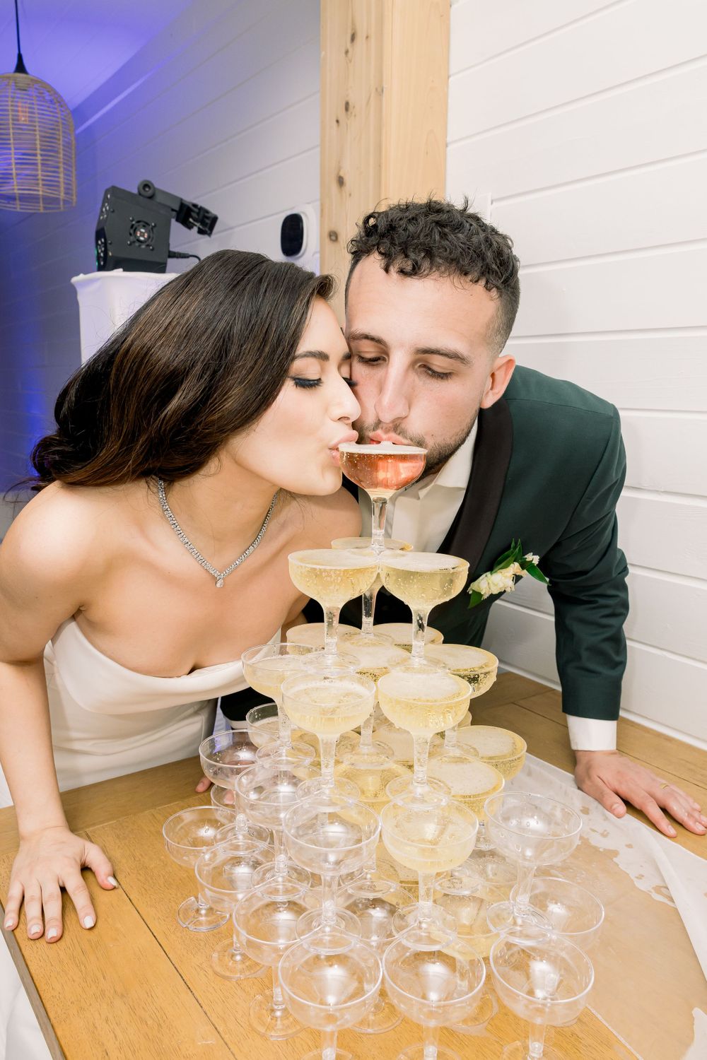 Wedding couple sharing a champagne glass from their champagne tower together.