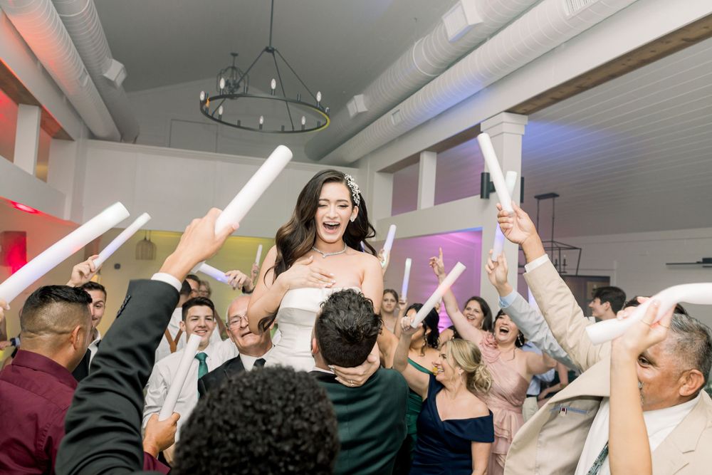Wedding reception guests lift the bride during a lively dance celebration.
