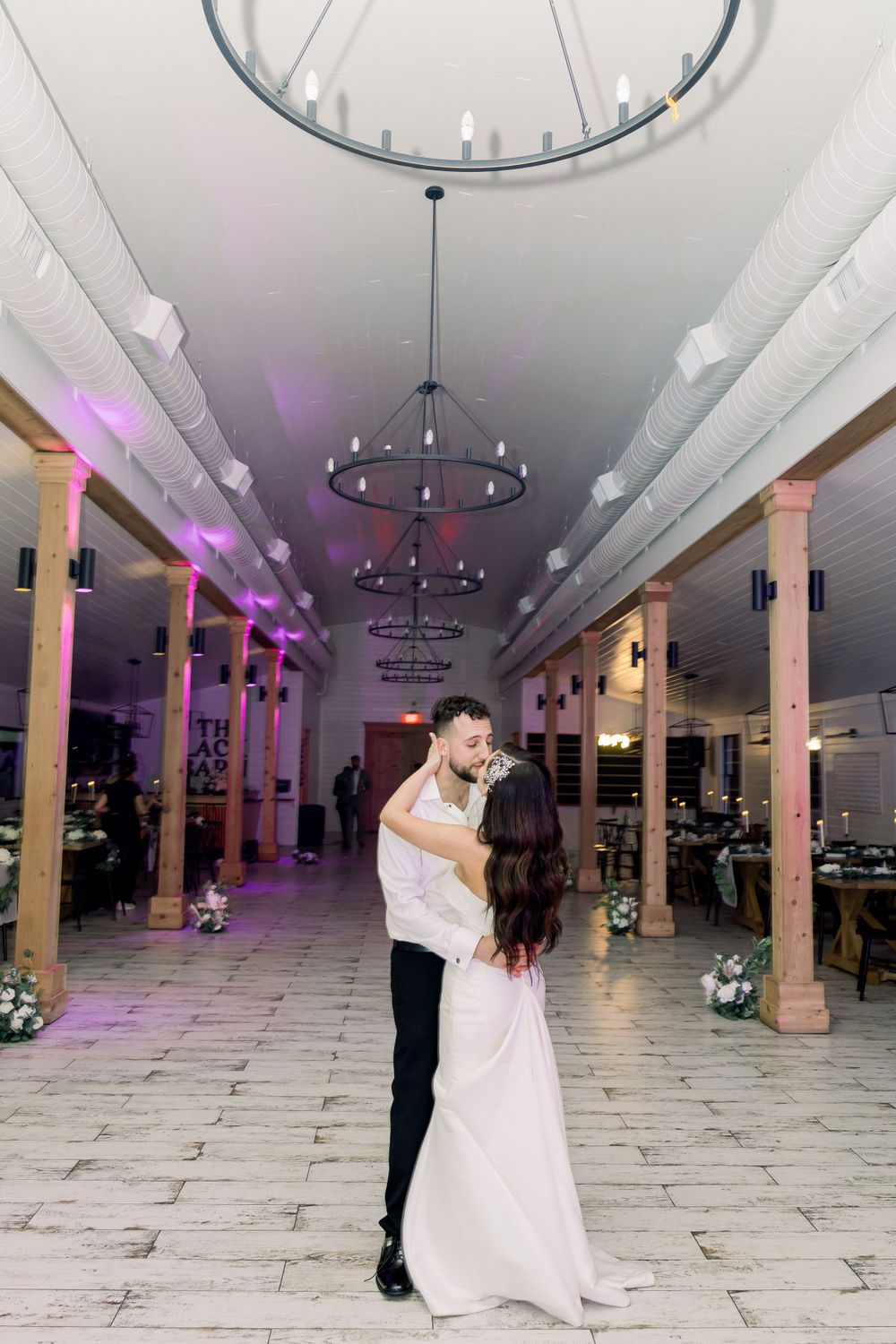 A romantic dance moment captured in an elegant reception venue with decorative lighting.