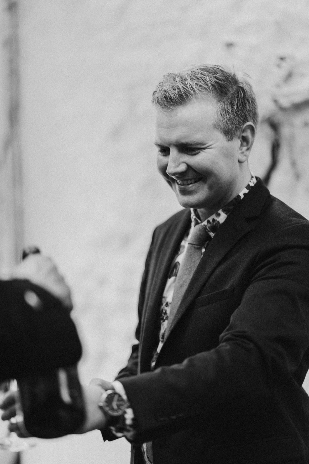 A candid black and white moment showing a person in a suit smiling warmly.