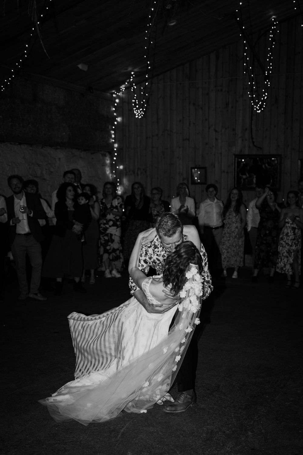 A romantic first dance at a wedding reception with string lights in the background.