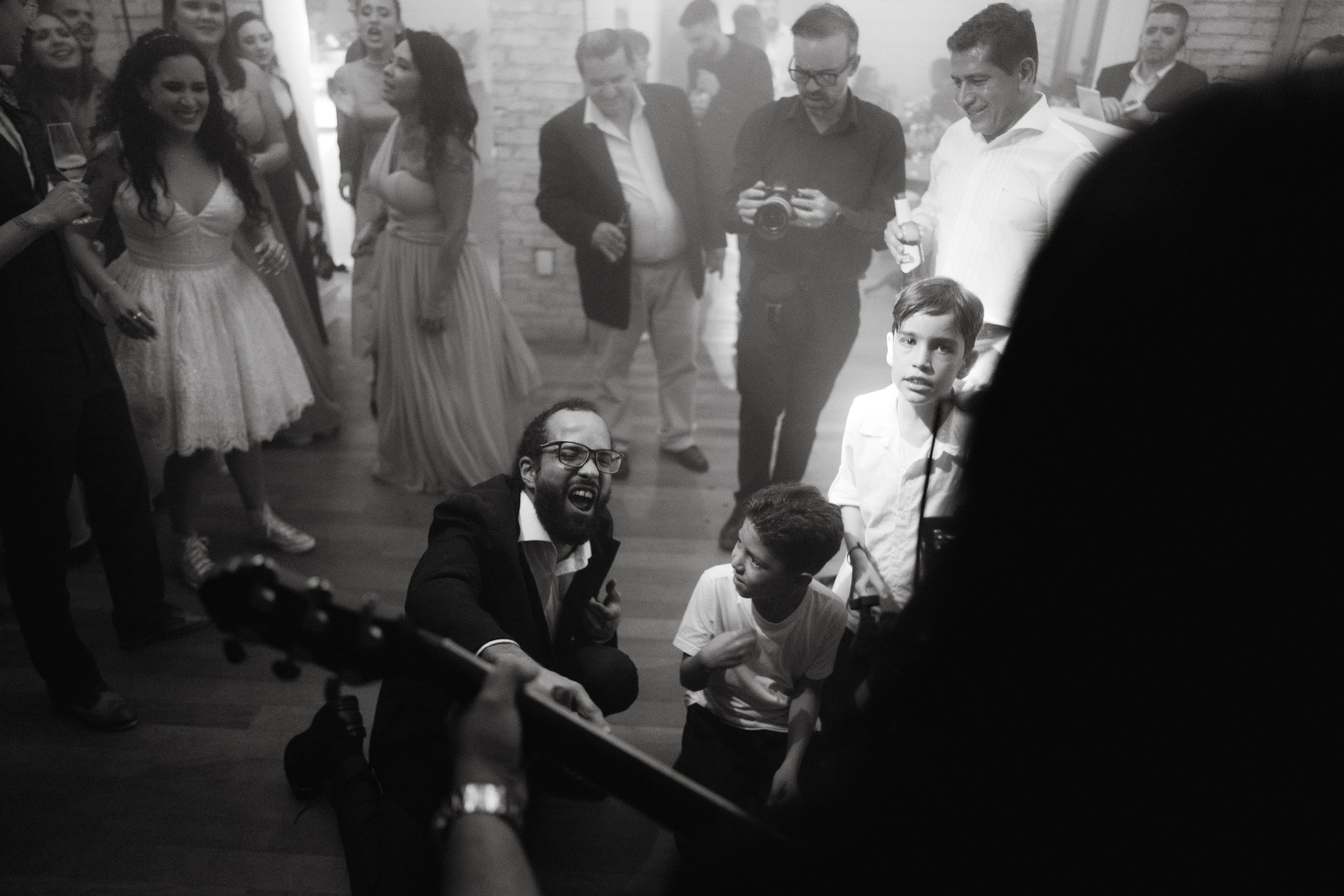Wedding celebration captured in black and white showing guests dancing enthusiastically.
